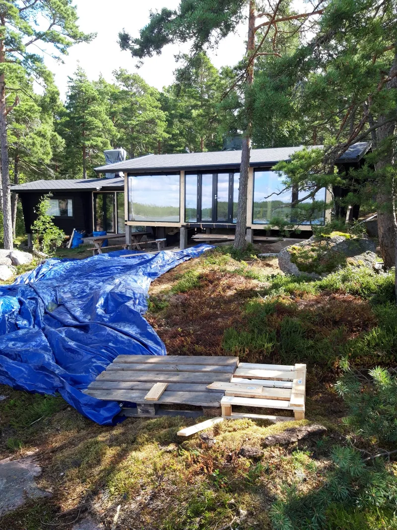 Musta fassaadi ja panoraamakendega suvemaja männimetsas
