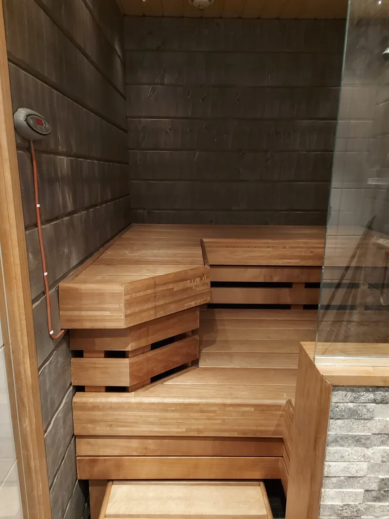 Sauna lavad ja tume seinaviimistlus kivivoodriga kerise taustal